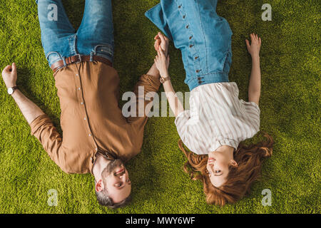 Vista superiore della coppia felice sdraiato sul prato verde e sorridente ogni altro Foto Stock