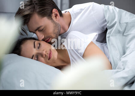 Il marito teneramente baciare la moglie dorme nel letto Foto Stock