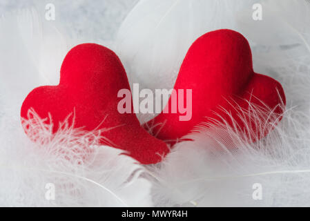 Due cuori rossi giacciono su fluff bianco. Metafora dell'amore. Biglietto di auguri per San Valentino sfondo minerale Foto Stock