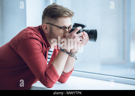 Giovane fotografo riprese con una fotocamera digitale da finestra di luce Foto Stock