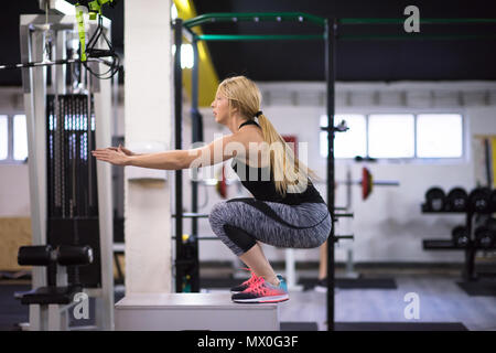 Atletica Giovane donna di salto di formazione sulla scatola adatta ad attraversare una palestra per il fitness Foto Stock