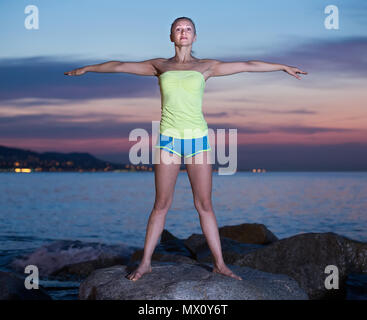 Giovane femmina la pratica dello Yoga asana al mare in serata per esterno Foto Stock