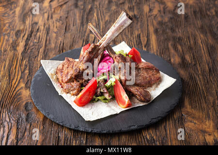 Ribeye sull'osso, Tomahawk, servita con pomodori e lattuga iceberg sulla pita sulla scheda di ardesia. Foto Stock