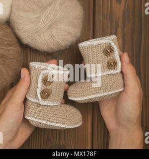 Baby scarpine per neonato in mani di madre, ragazza incinta con mano knetted scarpe per bambini aspettano baby gravidanza concetto. Scarpine per neonato Foto Stock