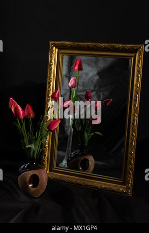 Abstract Magic. Tulip fiori in camera oscura riflettendo a specchio con baguette oro Foto Stock