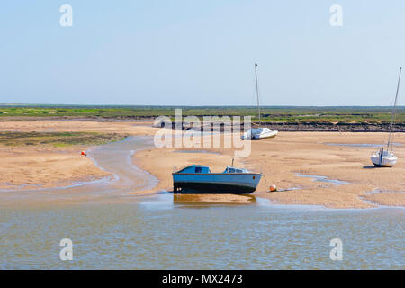 In estuario a bassa marea una vecchia imbarcazione a motore, catamarano e piccolo yacht stand sulla sabbia tra pozze di marea e di correnti Foto Stock