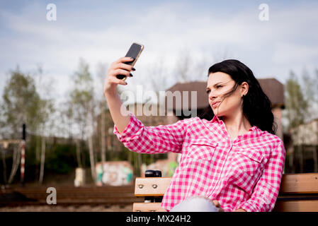 Ragazza sorridente facendo un selfie, una donna è di scattare una foto su reti sociali. Foto Stock