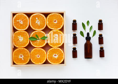 Bottiglia di olio essenziale di arance agrumi con succo di arancia e foglie su sfondo bianco. Foto Stock