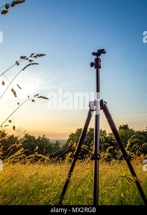 Un treppiede in piedi in un campo durante il tramonto Foto Stock