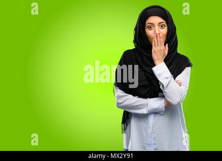 Giovane donna araba indossa hijab copre bocca in stato di shock, guarda timido, esprimendo il silenzio e confondere i concetti, paura Foto Stock