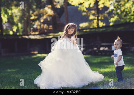 Felice bambina con le braccia aperte in estate in un abito bianco Foto Stock