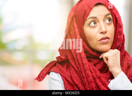 Giovane donna araba indossa hijab il pensiero e la ricerca di esprimere dubbi e meraviglia Foto Stock