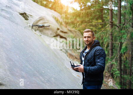 Guy inizia un quadrocopter nella foresta Foto Stock