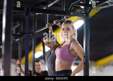 Un gruppo di giovani atleti muscolare facendo tirare ups sulla barra orizzontale come parte del Cross fitness training Foto Stock