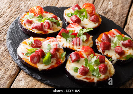Estate cibo: melanzane calda con formaggio, pomodori, salsiccia e salsa close up su una scheda di ardesia sul tavolo orizzontale. Foto Stock