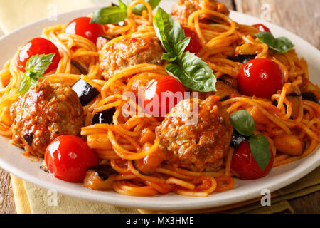Deliziosa la pasta tradizionale spaghetti con le polpette di carne, le melanzane in salsa di pomodoro close-up su una piastra su un tavolo. Posizione orizzontale Foto Stock