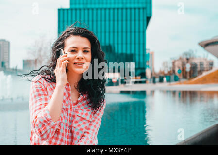 Donna che parla al telefono. Autenticità e spontaneità. Autentica conversazione al telefono. La ragazza in occhiali da sole possiede un telefono cellulare in mano. Foto Stock