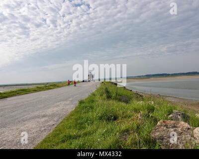 La gente a piedi, in moto e in bici oltre la serratura sulla baia di Somme, Le Crotoy, Francia Foto Stock