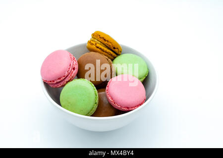 Macarons nella ciotola, dolci macaron colorati su sfondo bianco Foto Stock