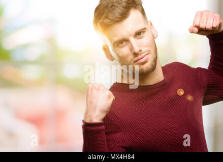 Bel giovane che mostra bicipite che esprime la forza e la palestra concetto, vita sana la sua buona Foto Stock