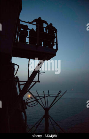 Golfo Arabico (29 aprile 2017) marinai a bordo guidato-missili cruiser USS Mare delle Filippine (CG 58) utilizzare un galleggiante di fumo per simulare un uomo in mare durante un drill come la portaerei USS George H.W. Bussola (CVN 77) (GHWB) transita nella distanza. Mare delle Filippine e GHWB sono distribuiti negli Stati Uniti Quinta Flotta area di operazioni a sostegno della sicurezza marittima operazioni destinate a rassicurare gli alleati e partner e preservare la libertà di navigazione e il libero flusso di commercio nella regione. (US Navy la comunicazione di massa specialista in seconda classe Patrick Ian Crimmins/rilasciato) Foto Stock