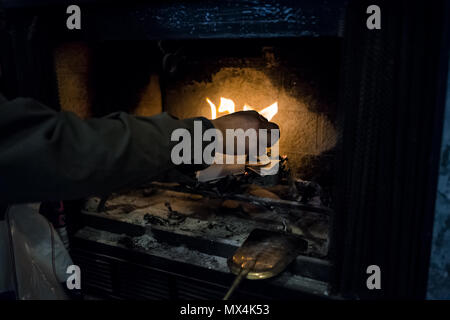 Man mano il raggiungimento di bruciare la carta in piscina home interno camino con il vecchio retro vintage golden oro strumenti strumenti, come pala, ceneri Foto Stock