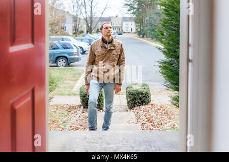 Giovane uomo in piedi sul portico anteriore frontyard passi davanti a casa home acquirente cercando di acquistare proprietà immobiliare client del cliente a townhouse risiedono Foto Stock