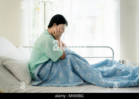 Asian giovane donna paziente sdraiato a letto di ospedale sensazione triste e depresso preoccupare. Malattia sensazione di malessere in materia di assistenza sanitaria e clinica il concetto di attenzione. Foto Stock