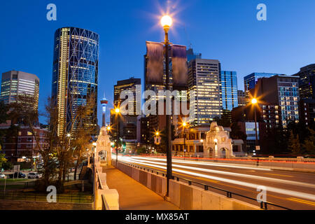 Sentieri di luce dal movimento vetture entrano Calgary quartiere finanziario del centro cittadino sulla strada del centro ponte che attraversa il Fiume Bow di notte tempo con la mitica C Foto Stock