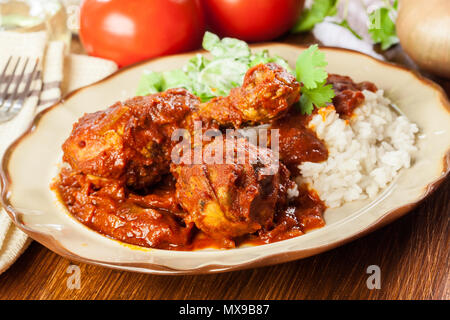 Coscia di pollo al curry con riso servito su una piastra Foto Stock