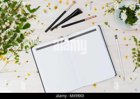 Da tavolo bianco scena con notebook bianco e matita nera con spazzole Foto Stock