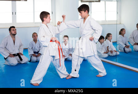 Gentile ordinary boys formazione in coppia per utilizzare la tecnica di karate durante la lezione Foto Stock