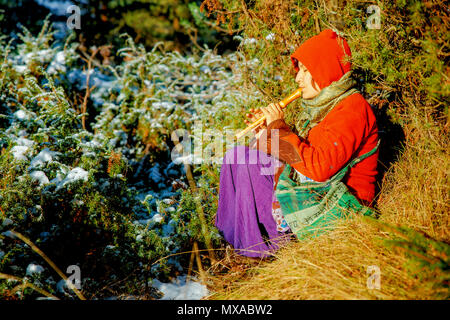 Bellissima ragazza in costume storico a giocare il suo flauto in foresta. Foto Stock
