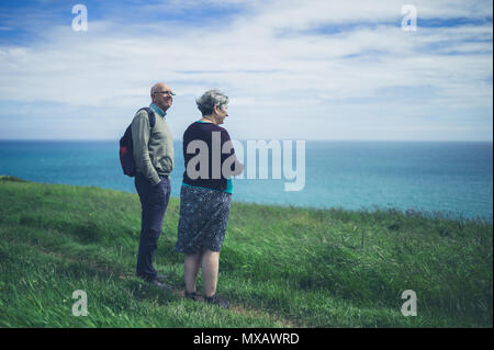 Una coppia senior è in riva al mare su una scogliera ammirando il paesaggio Foto Stock