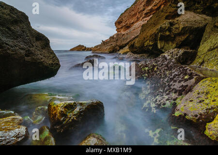 Tramonto sulla spiaggia tra le rocce vicino alla città di Denia. Distretto di Valencia, Spagna. Foto Stock