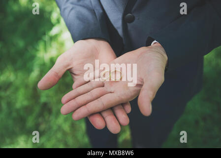 Due golden gli anelli di nozze su govern palms. Gli anelli di nozze sul palm. Foto Stock