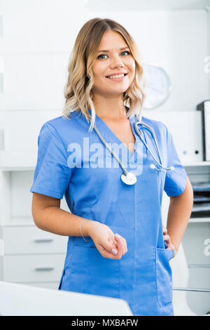 Ragazza medico sorge nei pressi di un tavolo in ufficio Foto Stock