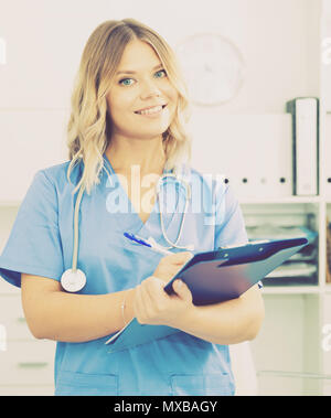 Ragazza medico sorge nei pressi di un tavolo in ufficio Foto Stock