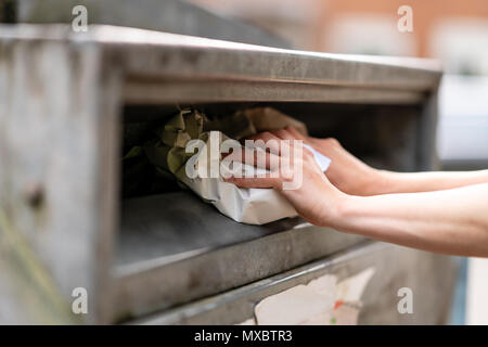 Donna mettendo la carta in un contenitore per il riciclaggio in Germania. Foto Stock