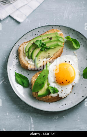 Sandwich di Avocado con uovo fritto - fette di avocado e uovo su pane tostato per una sana prima colazione o uno spuntino, copia dello spazio. Foto Stock