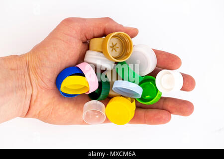 In plastica colorata i tappi di bottiglia in una mano umana. Studio shot. Rifiuti di plastica. Isolato su uno sfondo bianco. Foto Stock