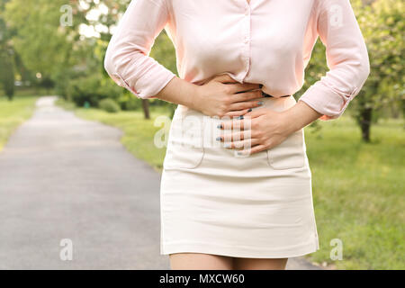 Giovane donna che soffre di dolori addominali mentre si cammina in posizione di parcheggio Foto Stock