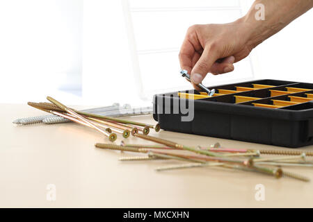 Lavoratore a mano scegli un dado viti dalla scatola, close up Foto Stock