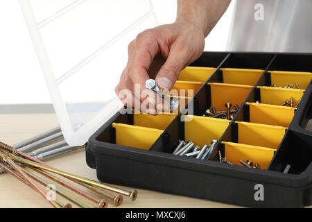 Lavoratore a mano scegli un dado viti dalla scatola, close up Foto Stock