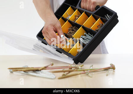 Lavoratore a mano scegli un dado viti dalla scatola, close up Foto Stock