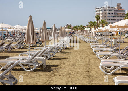 Larnaca, Cipro, Makenzie beach. Vuoto di sedie a sdraio e ombrelloni sulla sabbia Foto Stock