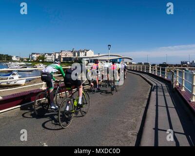 Un gruppo di ciclisti attraversando ponte girevole verso la piscina e il Parco Mooragh Ramsey Isola di Man sul bel giorno di maggio con il blu del cielo Foto Stock