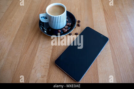 Smartphone oltre a caffè sul tavolo di legno con i chicchi di caffè Foto Stock