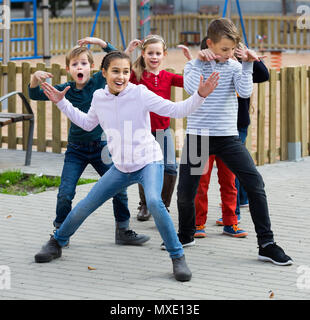 Felice bambini spagnoli che mostra diverse figure durante le fasi di gioco nel parco giochi all'aperto Foto Stock