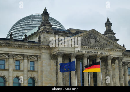 Berlino, Germania - 14 Aprile 2018: Frontone con colonne e la cupola del Reichstag con il tedesco e l'Unione europea bandiere in primo piano Foto Stock